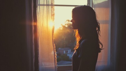Silhouette of a Woman at Sunset Viewed Through a Window with Sheer Curtains