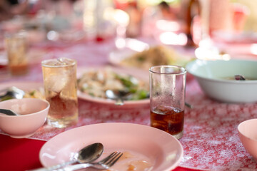 Close-up of a Thai party table with soda and diluted whiskey in glasses, surrounded by shared dishes on a red tablecloth.
