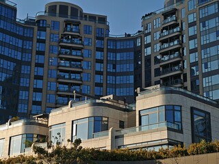 Modern Hong Kong apartment buildings; sleek, glass-fronted high-rises and a lower, cream-colored...