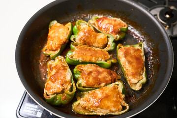 フライパンで調理中の肉詰めピーマン