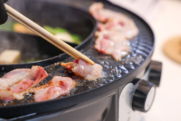 Party for barbecue japanese style, yakiniku. Meats are being cooked on stove frying pan