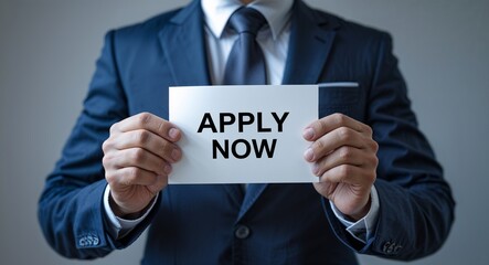 apply now text on plain white paper in hand on guy on formal suit business concept background