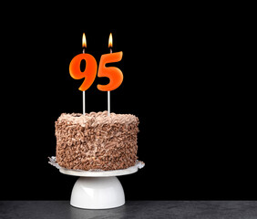Birthday card with candle number 95 - Chocolate cake on black background.
