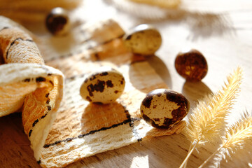 Quail eggs on wooden background, home decorations.  Soft morning sunlight, cozy home. Happy Easter. Brown beige colors
