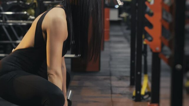 A young girl athlete trains in a fitness club doing squats with a barbell. Girl training in the gym. Modern gym.