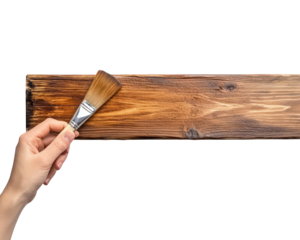 hand holding brush is painting wooden plank, showcasing craftsmanship and creativity. rich texture of wood enhances artistic process