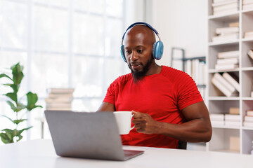 Mature Caucasian African American in headphones working at his workplace office.