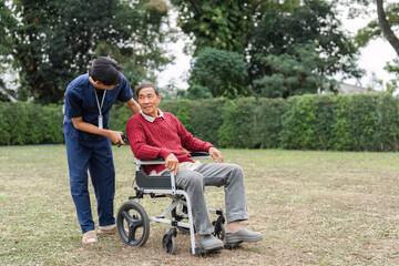 Nursing aide engaging with elderly man in wheelchair, encouraging conversation in tranquil garden