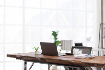Laptop Computer, notebook, office space ,and eyeglasses sitting on a desk in a large open plan office space after working hours	