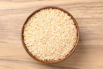 Organic Jasmine brown rice seed in bowl on wooden background, Thai Rice, Table top view