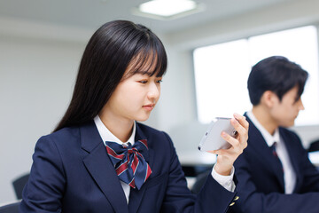 授業中に携帯電話を使用するアジアの 10 代の少女