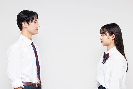 向かい合って立っている制服を着たアジアのティーンエイジャー