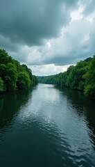 Fototapeta premium Dark grey clouds over a serene river with ripples on the water, greenery, atmosphere, peaceful