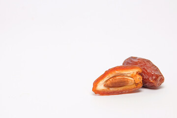 Close up of sliced fruit and ripe date seeds isolated on white background. Fruit typical of the Arab region. Sweet and legit taste.Copy space for text.For graphic design or banner background