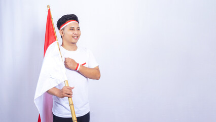 Indonesian Young Man Raising Fist in front of His Chest while Holding Country Flag Isolated on White Background