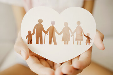 Hands holding multi generational family paper in heart shape, family wellness, health insurance concept.