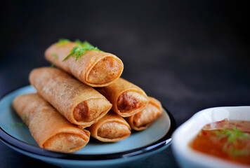 Deep fried spring roll in golden brown color, served in a blue oval shape plate, famous local street food in Thailand, food industry concept
