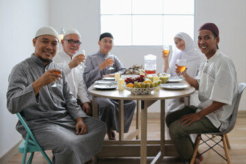 Portrait Of Asian Muslim Family Smiling While Showing Glass Of Tea To Drink During Eid Mubarak Moment 