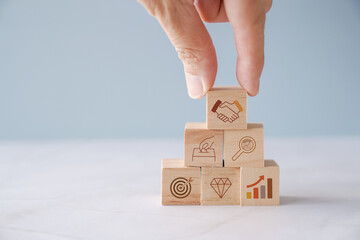 Hands holding wooden blocks with ETF and icons, exchange traded funds, retirement plan concept.