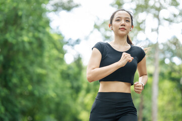 Fototapeta premium A woman in sportswear running in the park, enjoying fresh air, engaging in outdoor activities to maintain a healthy lifestyle, boosting cardiovascular health, and feeling happy and energetic