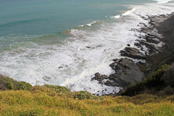 Ocean waves crashing onto rocks from an elevated perspective