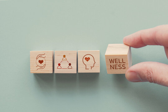 Hands holding wooden cube blocks with wellness icons, positive mental health, life balance concept.