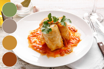 Plate with tasty stuffed cabbage rolls on light wooden background