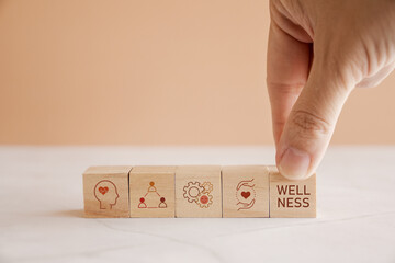 Hands holding wooden cube blocks with wellness icons, positive mental health, life balance concept.