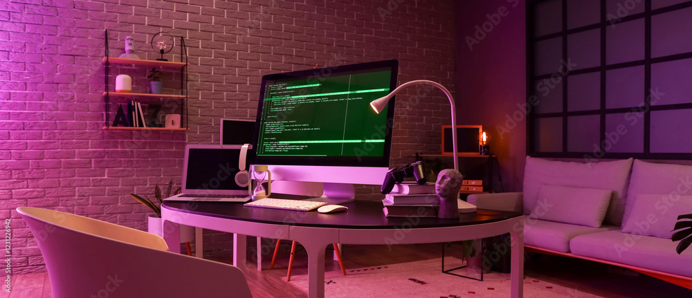 Wall mural programmer's workplace with computer, laptop and glowing lamp in dark office