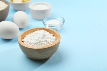 Baking powder and other ingredients for making dough on light blue background, space for text