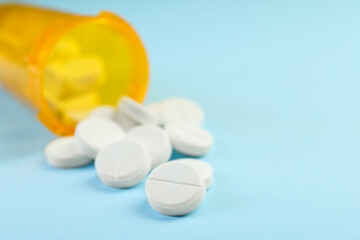 Bottle of antibiotic pills on light blue background, closeup. Space for text