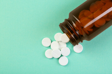 Bottle of antibiotic pills on turquoise background, top view. Space for text