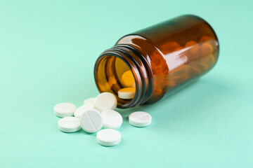 Bottle of antibiotic pills on turquoise background, closeup