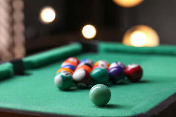 Billiard balls in triangle on green table indoors, closeup. Space for text