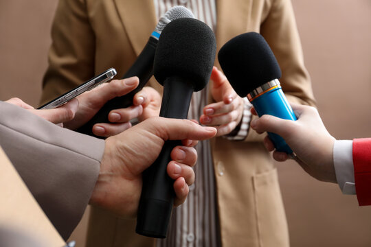 Group of journalists interviewing businesswoman on beige background, closeup