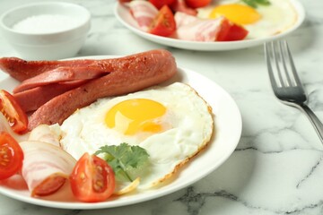Tasty brunch. Fried egg, sausage, bacon and tomatoes on white marble table, closeup