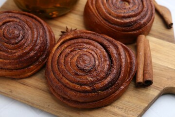 Delicious cinnamon rolls and spices on white table, closeup