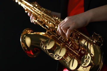 Obraz premium Professional musician with saxophone on black background, closeup