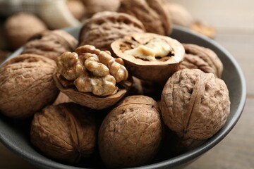 Fresh walnuts in bowl on table, closeup