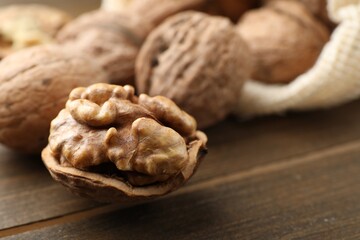 Fresh walnuts with shells on wooden table, closeup. Space for text