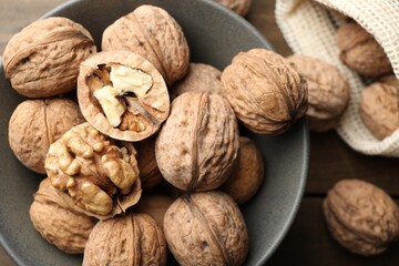 Fresh walnuts in bowl and bag on table, flat lay