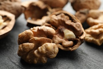 Fresh ripe walnuts and shells on black table, closeup