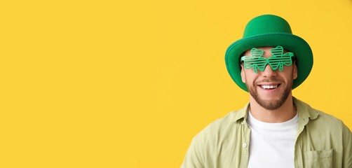 Young man wearing leprechaun's hat and party glasses on yellow background with space for text. St....