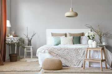 Interior of cozy bedroom decorated with chrysanthemum flowers and blooming tree branches