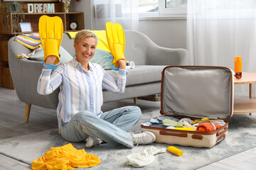 Mature woman with flippers packing suitcase at home © Pixel-Shot
