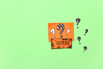 Paper quiz card with question marks on green background