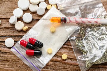 Syringe and different drugs on wooden background, closeup