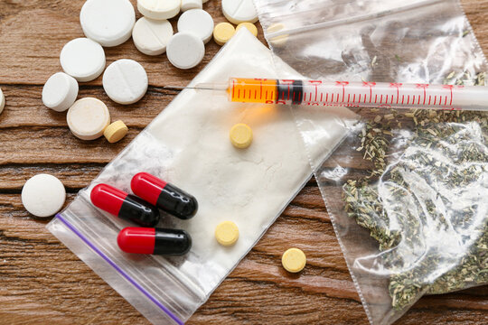 Syringe and different drugs on wooden background, closeup
