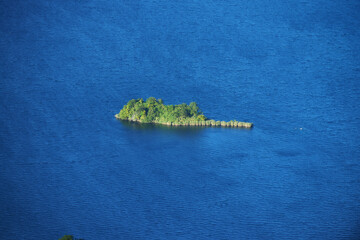 A serene daytime view of Lake Ilopango, El Salvador, showcasing its volcanic crater, calm waters, and lush surrounding landscapes.