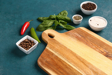 Wooden cutting board with aromatic spices on color background, closeup